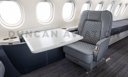 Gray club seat with white conference table in Falcon 2000