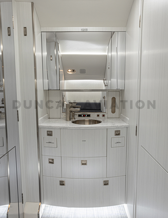 All white lavatory with gold hardware in Falcon 2000 interior refurbishment