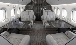 Gray club seats with conference tables inside Falcon 2000