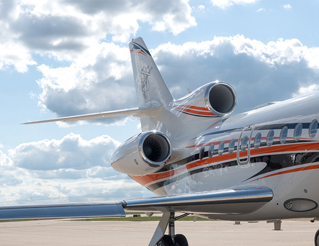 Photo of rear tail and engines on a Falcon 900 with newly painted exterior in white with dynamic orange and navy stripes