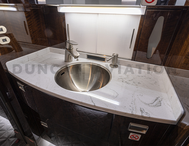 Lavatory sink with marble counter and dark wood cabinet in Falcon 900