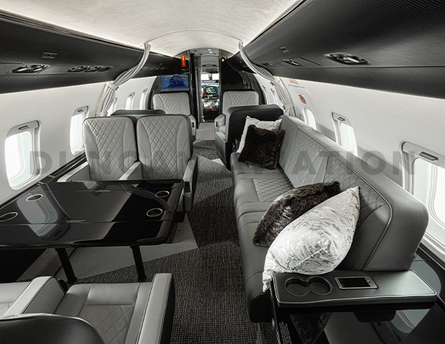 Interior of refurbished Challenger 604 with gray leather upholstered divan with accent pillows and club seat with conference table