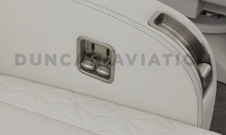 Close up of arm rest wrapped in white leather with brushed sliver seat levers