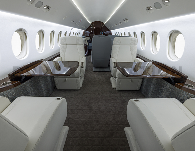 White leather seats with dark wood tables in Falcon 900