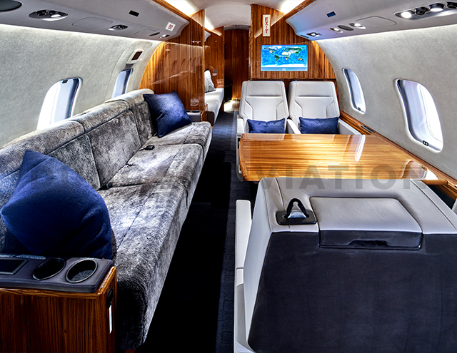 Plush gray divan, white leather seats, warm wood table in refurbished Global Express