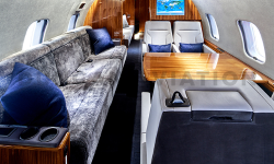 Plush gray divan, white leather seats, warm wood table in refurbished Global Express