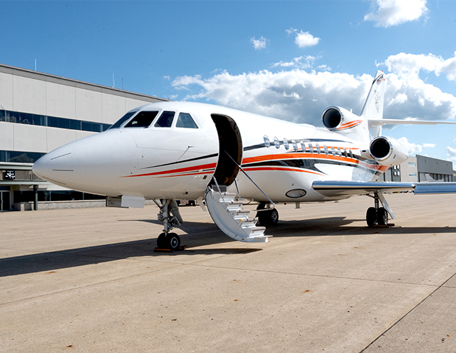Falcon 900 with cabin door open, newly painted white with orange and navy stripes by Duncan Aviation