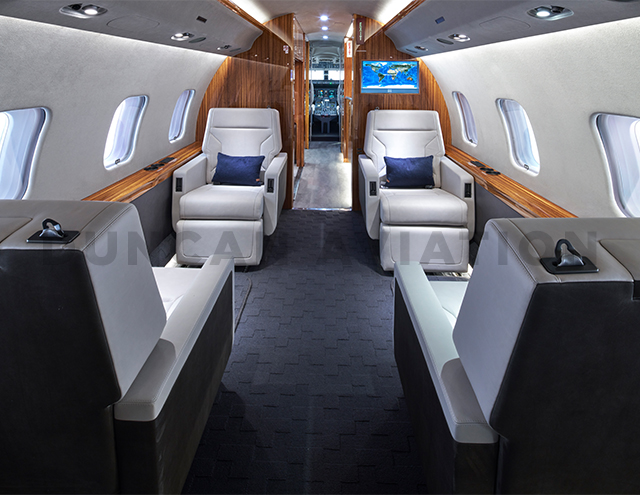 Refurbished interior of Global Express with white leather seats, dark gray carpet and warm wood tones by Duncan Aviation