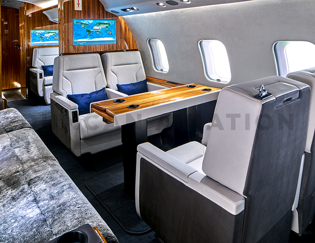 Double white leather seats with warm wood table in Global Express refurbished by Duncan Aviation