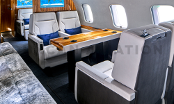 Double white leather seats with warm wood table in Global Express refurbished by Duncan Aviation