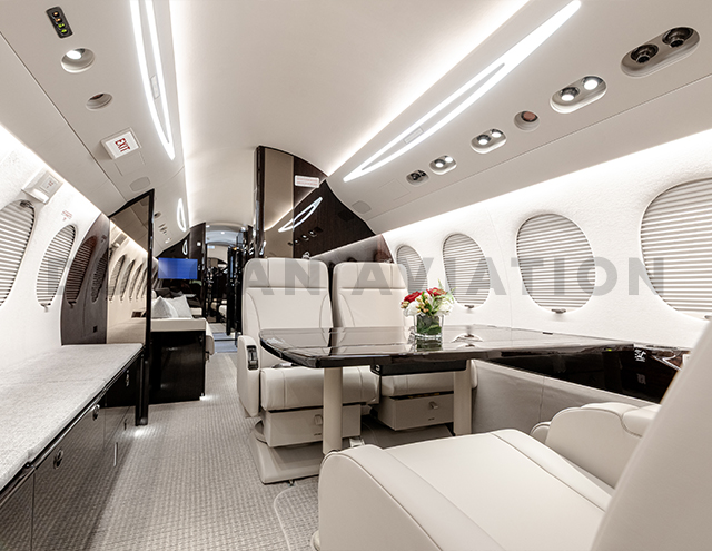 Creamy interior of refurbished Falcon 7X with dark wood accents by Duncan Aviation