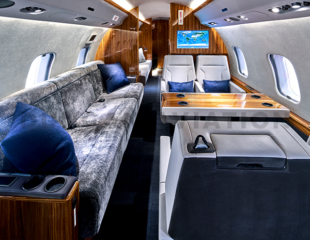 Plush gray divan, white leather seats, warm wood accents in refurbished Global Express