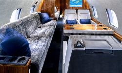 Plush gray divan, white leather seats, warm wood accents in refurbished Global Express