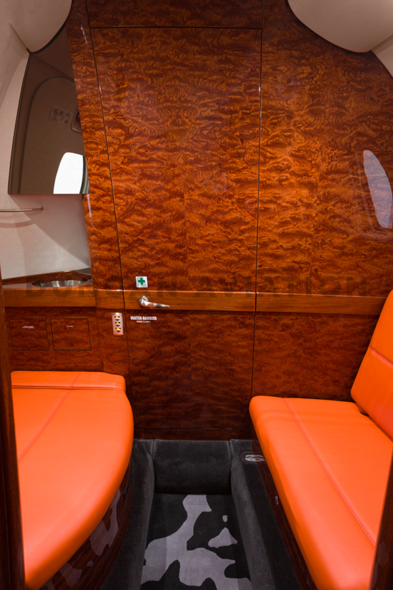 Interior of Citation 560XL with wood cabinets and orange seating