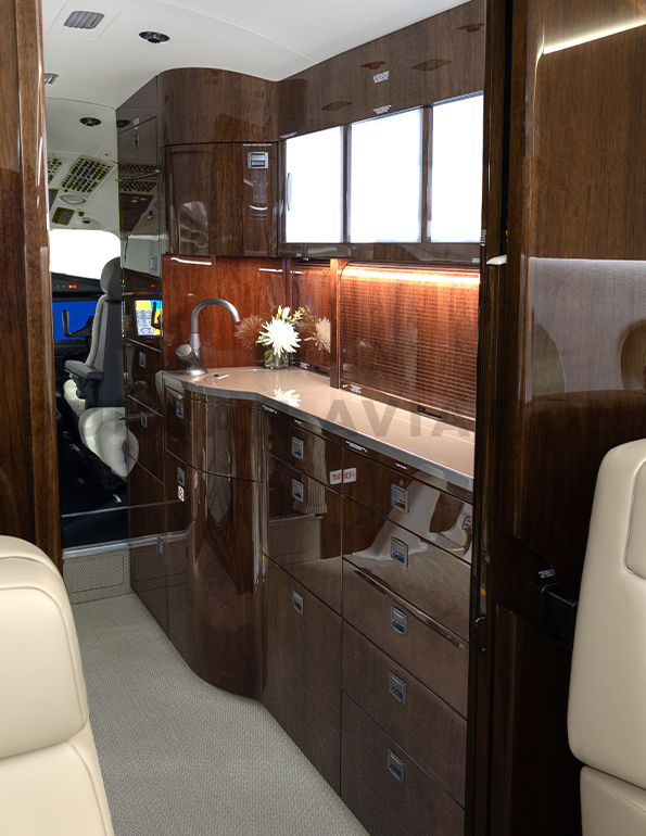 Galley in newly refurbished Falcon 2000 featuring dark wood tones and ample lighting