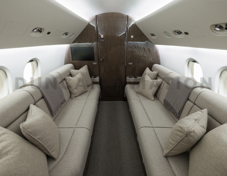 Two divans facing each other in cool beige leather with dark carpet and dark wood on Falcon 900 refurbished by Duncan Aviation