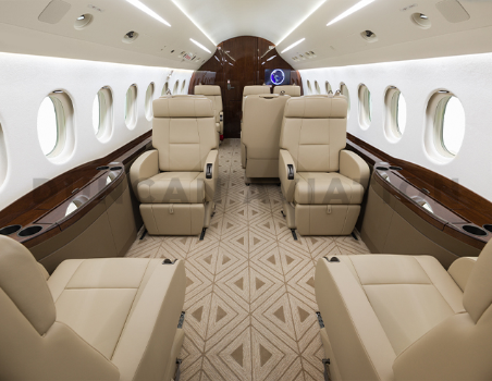Newly refurbished interior of Falcon 2000 by Duncan Aviation showing 10 leather seats, tan geometric carpet and dark wood accents
